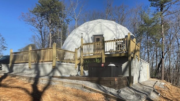 A dome-shaped structure with a wooden deck and a concrete pathway leading to it. - Charming 2-bedroom cabin with AC in peaceful Hays (Hays)