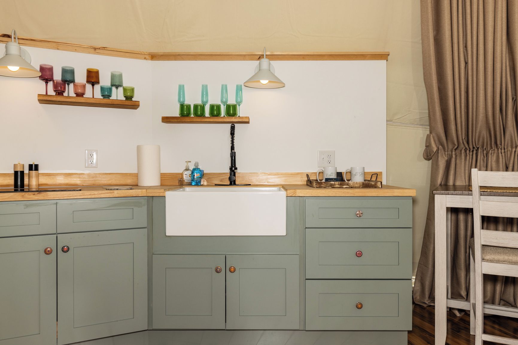 Une cuisine avec un plan de travail en bois, un évier et une fenêtre avec des rideaux.