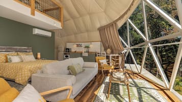 A tented accommodation with a bed, sofa, and dining area.