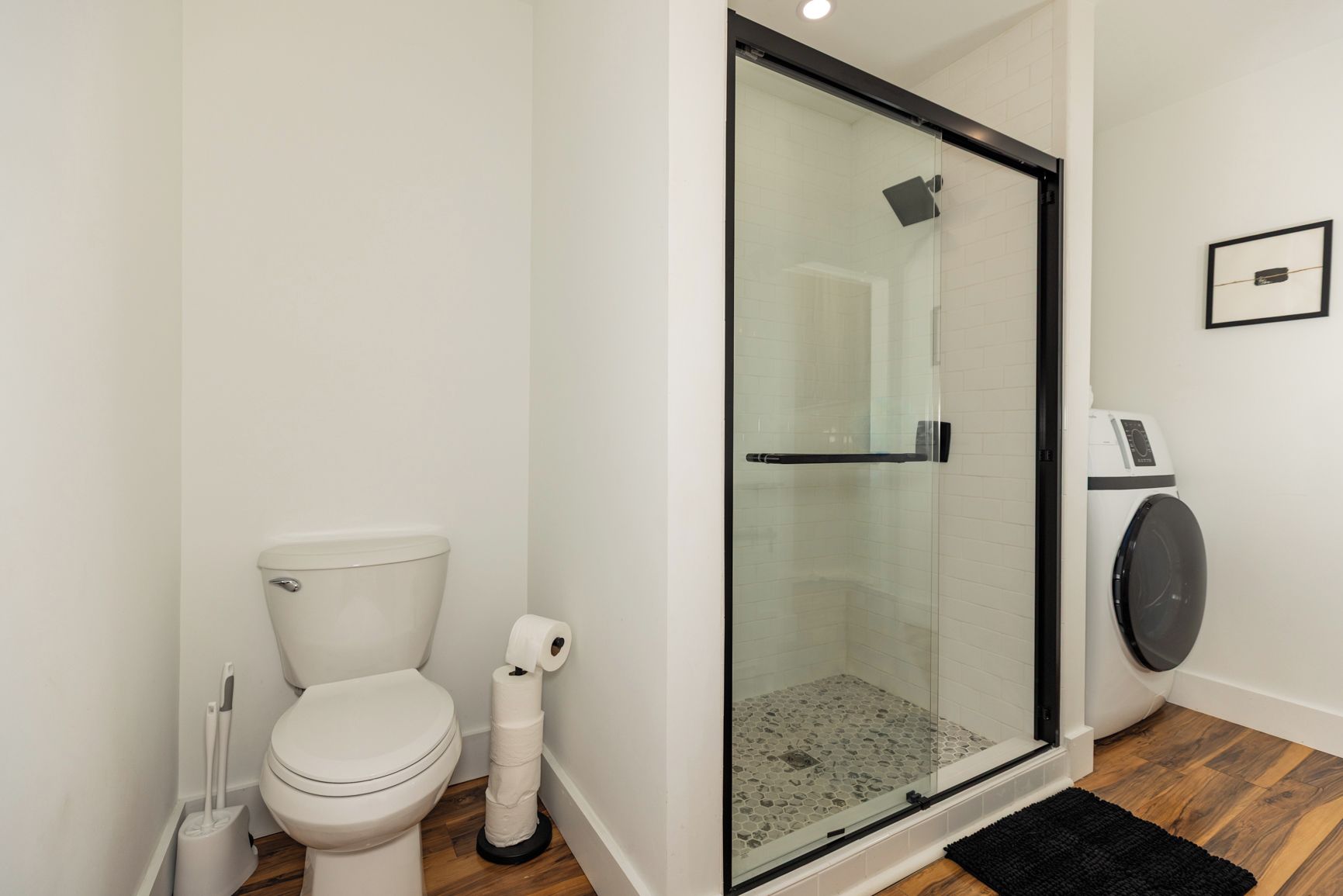 Ein Badezimmer mit Toilette, einer Duschkabine und einer Waschmaschine.