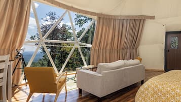 A bedroom with a large window, a telescope, a sofa, and a bed.