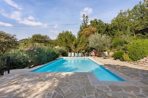 A rectangular swimming pool with a stone border, surrounded by lush greenery and trees. - Holiday Home 'Annette' with Mountain View, Wi-Fi and Air Conditioning (Bargemon)