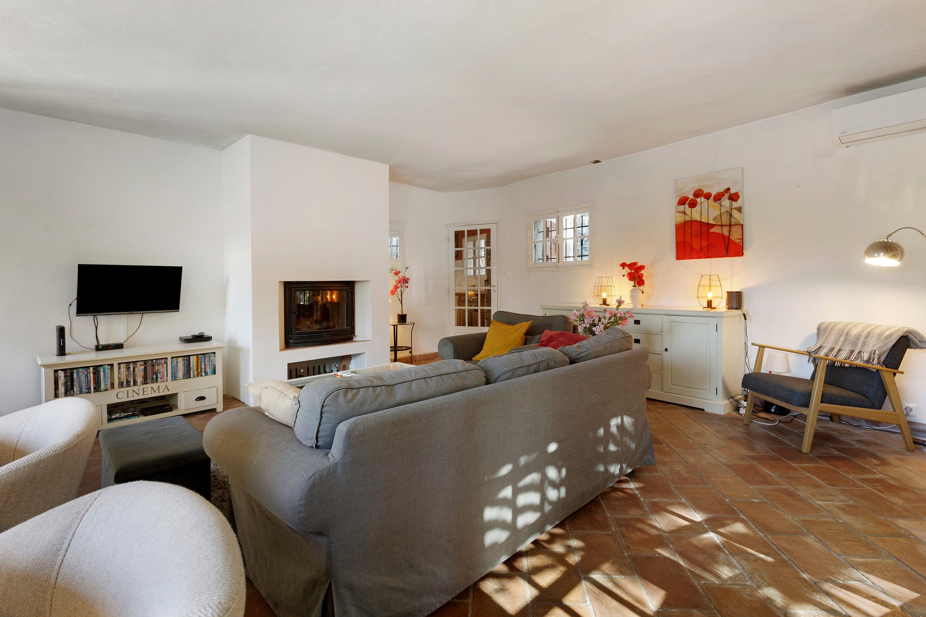 Een woonkamer met een bank, televisie, boekenkasten en een open haard.