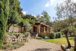 A stone house with a covered porch, surrounded by a gravel path and lush greenery. - Holiday Home 'Annette' with Mountain View, Wi-Fi and Air Conditioning (Bargemon)
