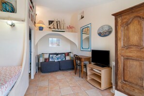 A compact living space with a bed, a sofa, a television, and a small table. - Holiday Home 'Au Bon Accueil' with Mountain View, Private Terrace and Wi-Fi (Fayence)