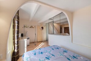Un dormitori amb un llit, un mirall, un radiador i una finestra amb cortines.