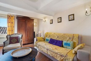 A living room with a sofa, armchair, and a small table with a tray. - Holiday Home 'Au Bon Accueil' with Mountain View, Private Terrace and Wi-Fi (Fayence)
