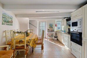 A kitchen with white cabinets, a Bosch oven, and a dining area with a yellow tablecloth. - Holiday Home 'Au Bon Accueil' with Mountain View, Private Terrace and Wi-Fi (Fayence)