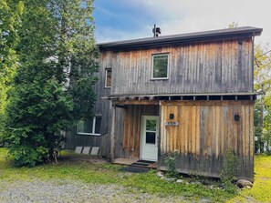 Ein zweistöckiges Holzhaus mit einer Haustür und einer kleinen Veranda.