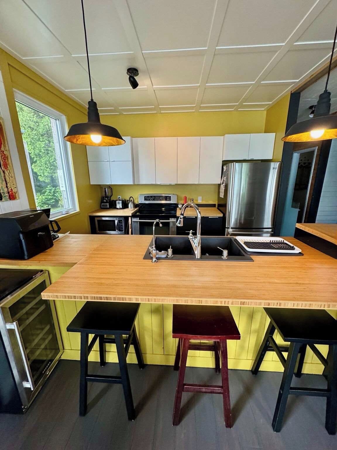 A modern kitchen with a central island, stainless steel appliances, and bar stools.