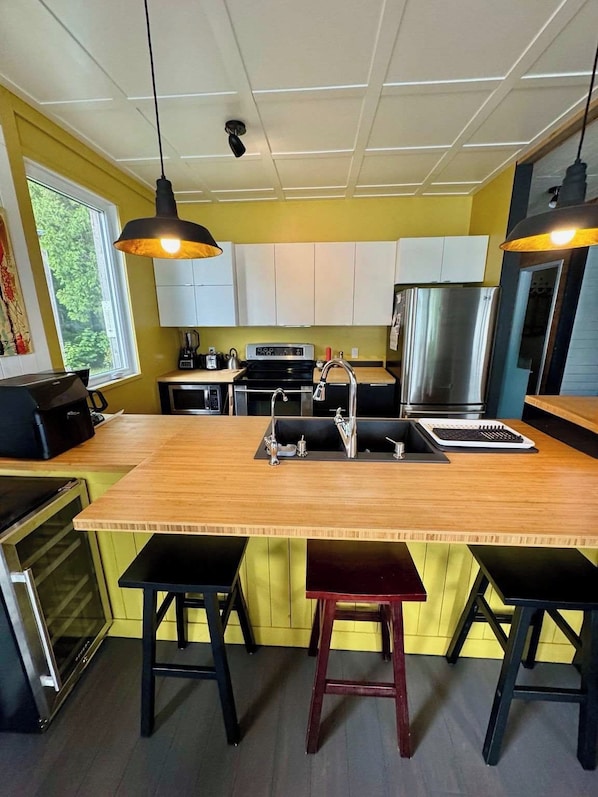 A modern kitchen with a central island, stainless steel appliances, and bar stools.