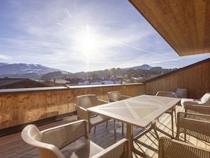 Una terraza de madera con una mesa y sillas, con vistas a un paisaje montañoso.
