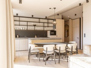 A modern kitchen with a central island, dining chairs, and built-in appliances. - Premium Penthouse With 3 Bedrooms (Oberndorf in Tirol)