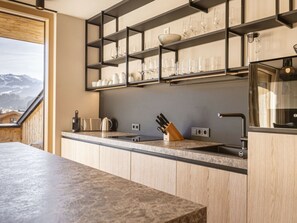 A modern kitchen with wooden cabinets, a marble countertop, and a built-in wine rack. - Premium Penthouse With 3 Bedrooms (Oberndorf in Tirol)