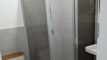 Un baño con cabina de ducha, inodoro y lavabo.
