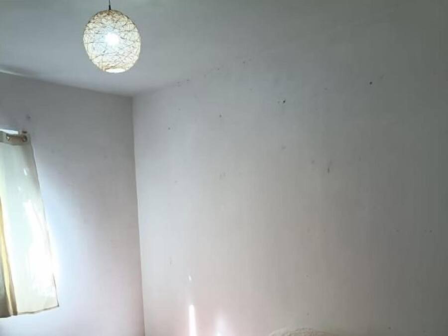 Una habitación con una cama, una ventana y una lámpara colgante.