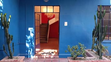 Pared exterior azul con una puerta que da a una escalera interior.