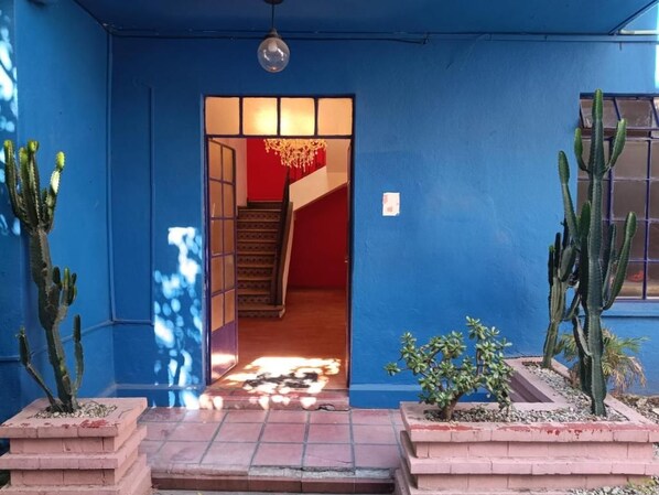 A blue exterior wall with a doorway leading to an interior staircase.