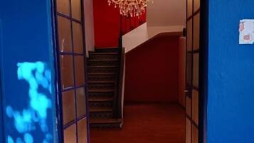 A hallway with a chandelier, a staircase, and a blue wall.