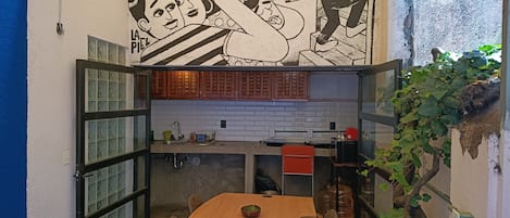 Eine kompakte Küche mit Essbereich, inklusive Wandgemälde, Holzschränken und einer gefliesten Spritzschutzwand.