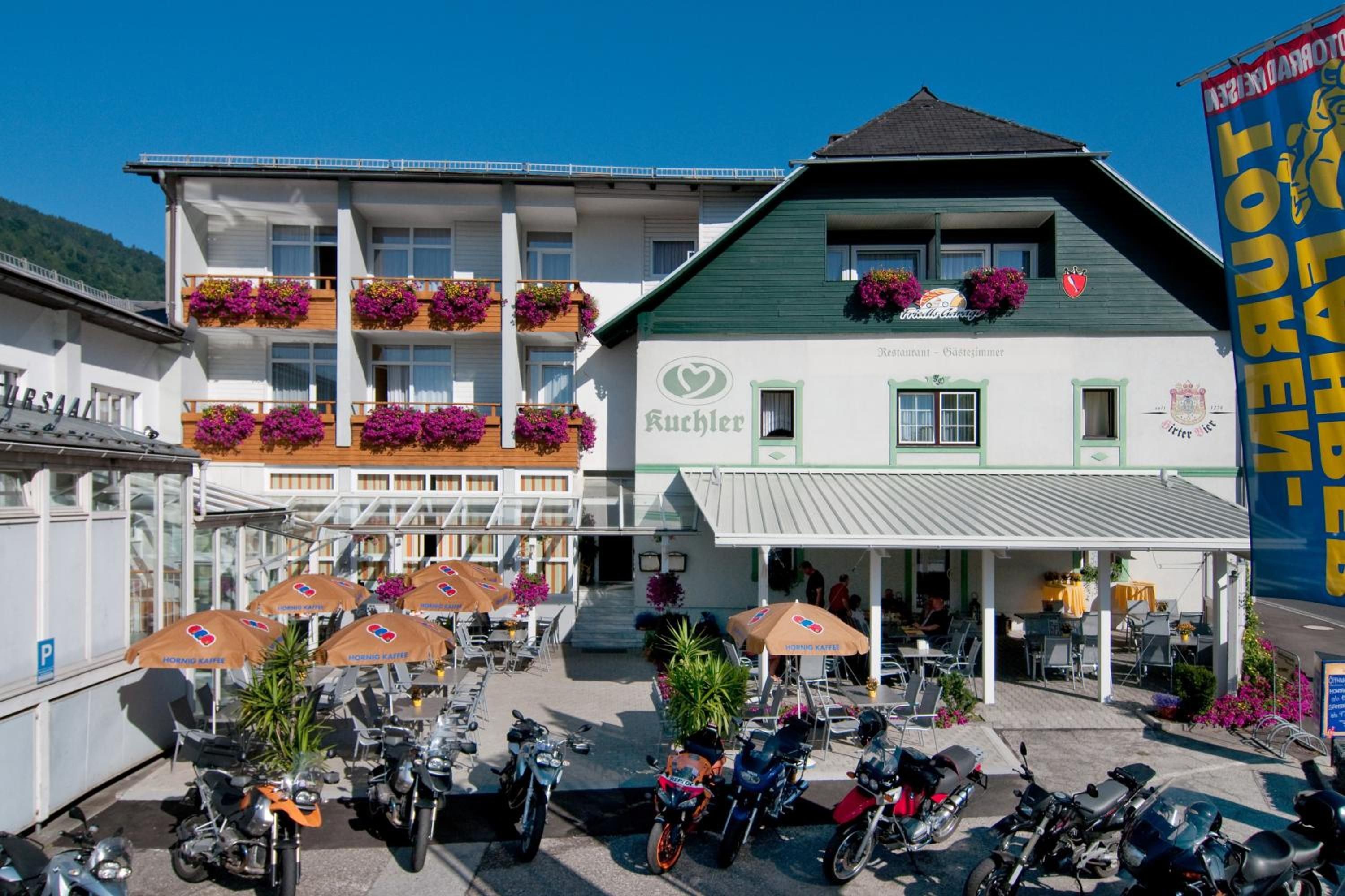 A building with a restaurant named 'Kuchler' on the ground floor, featuring outdoor seating with umbrellas.