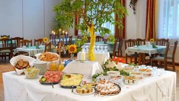 A breakfast buffet with a variety of food items, a centerpiece with a tree, and a casual dining atmosphere.