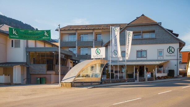 Un hotel con fachada moderna, varios balcones y una entrada destacada con toldo de cristal.