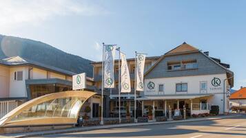 Ein Hotel mit mehreren Flaggen, einem überdachten Eingang und einer Bergkulisse im Hintergrund.