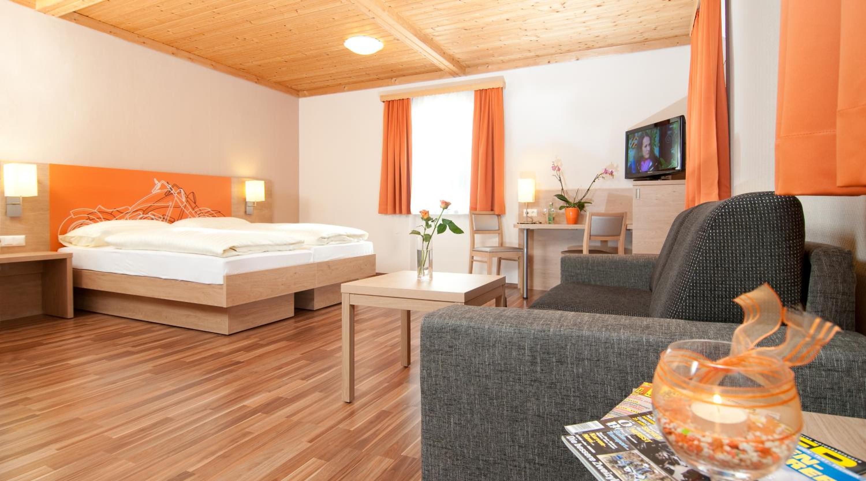 A hotel room with a bed, a desk, a chair, and a television.