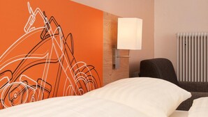 Una habitación de hotel con una cama, una lámpara de pared y un radiador.