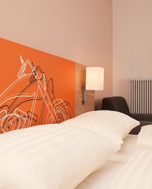 Una habitación de hotel con una cama, una lámpara de pared y un radiador.