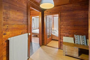 A wooden cabin interior with a bed, a bench, and a radiator. - Family-friendly chalet with a magnificent view and a terrace (Euseigne)