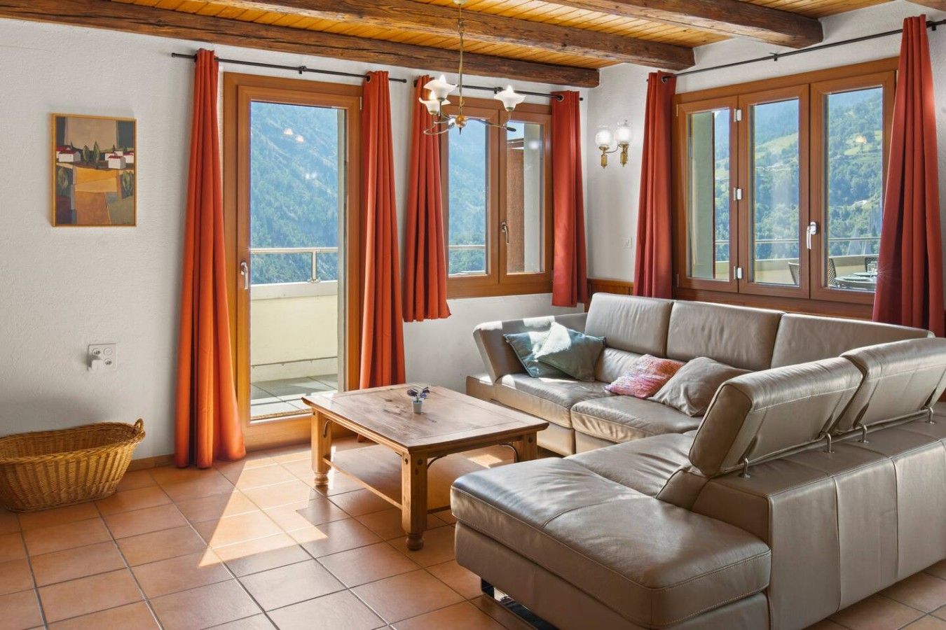 A room with a sofa, a wooden table, and a view of the outdoors.
