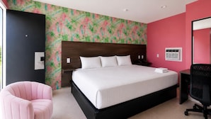 A modern bedroom with a large bed, a pink chair, and a desk with a chair. - Pet-Friendly with Gulf Views | Steps to St. Joe Beach – Mod Mahjong (Port St Joe)
