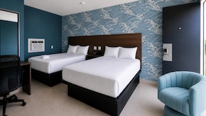 Une chambre d’hôtel avec deux lits, une chaise bleue, un bureau et un mur à motifs.