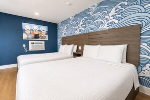 Ett hotellrum med två sängar, en sänggavel i trä och en blå vägg med vågmönster.