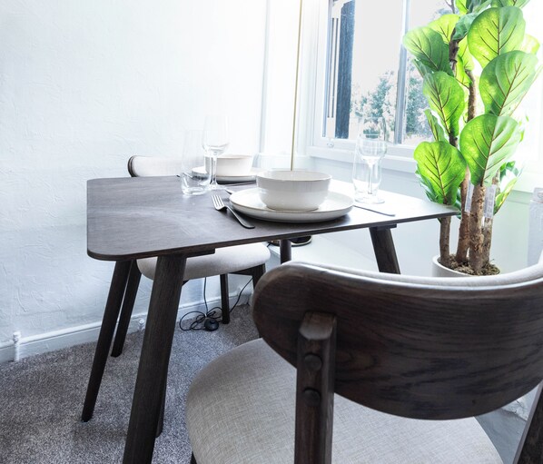 A dining table with a potted plant, a bowl, and a glass.