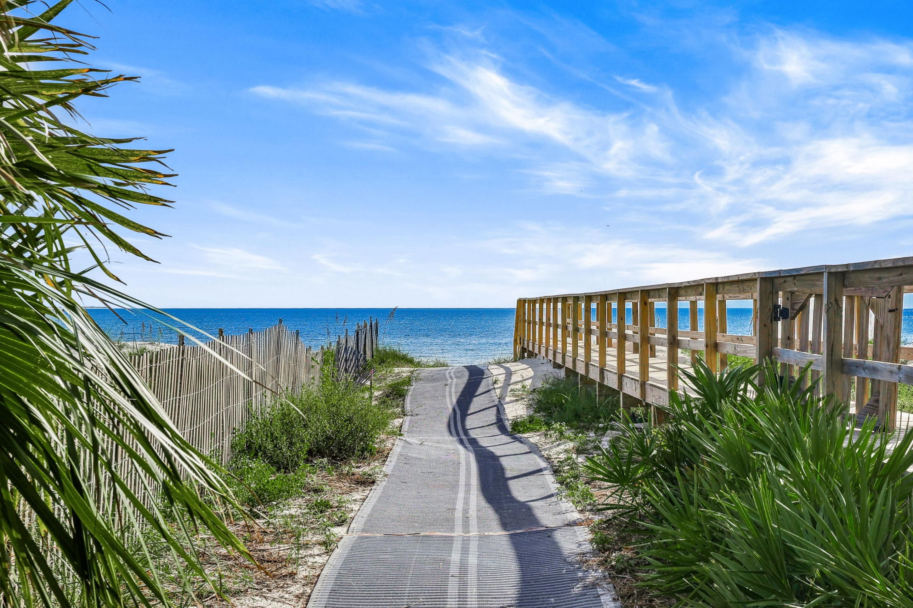 A wooden boardwalk leading to a beach with clear skies.