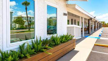 A hotel with a row of rooms, a covered walkway, and a parking lot.