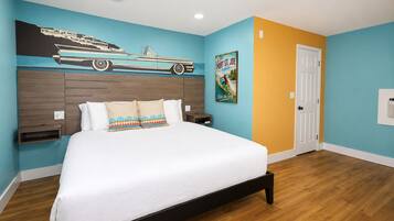 Une chambre à coucher avec un lit, une tête de lit ornée d’une fresque représentant une voiture, une affiche et une porte.