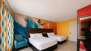 Quarto de hotel com duas camas, uma escrivaninha, uma cadeira e um mural de um surfista.