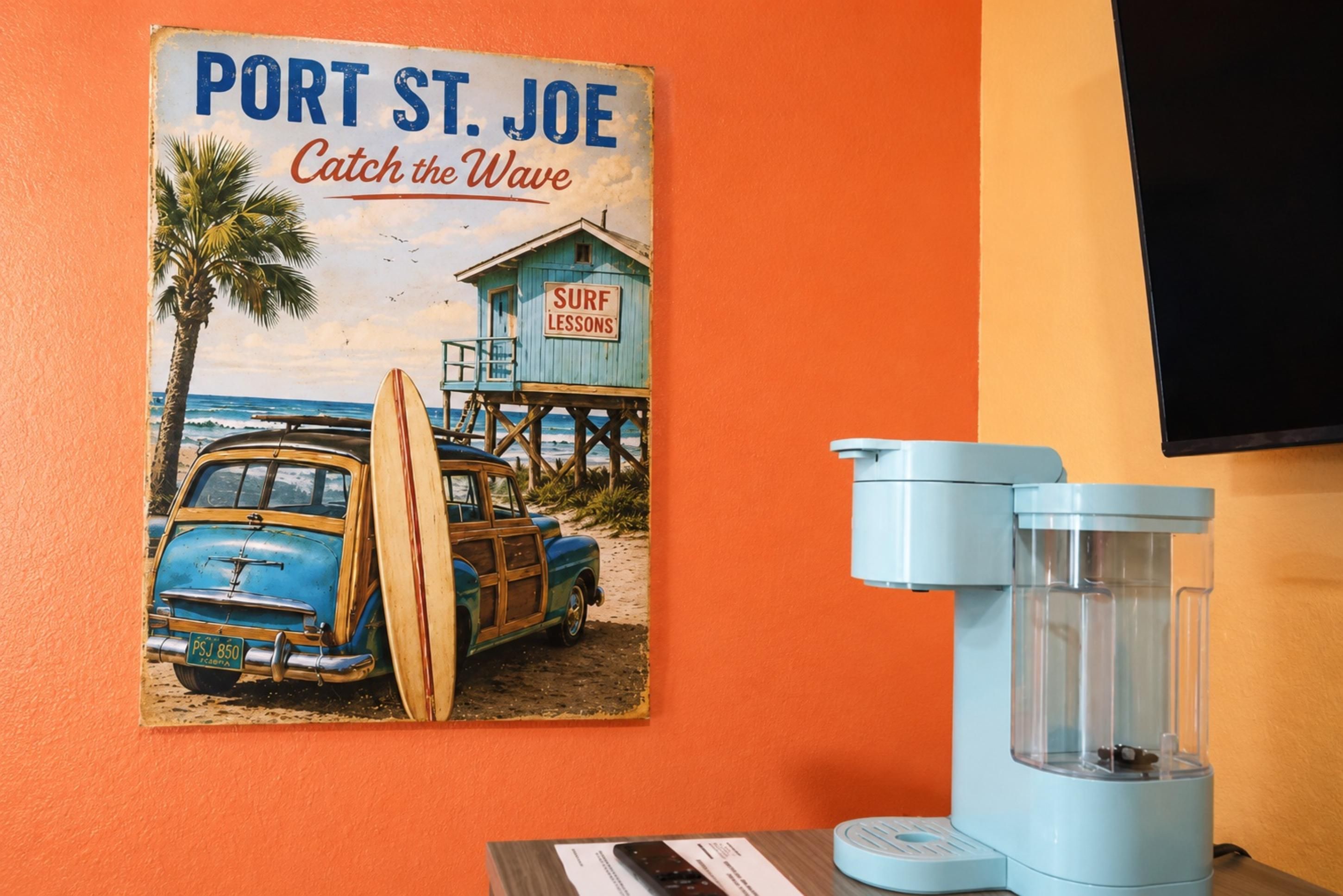 Póster antiguo de Port St. Joe con clases de surf, un coche azul y un filtro de agua azul sobre una mesa.