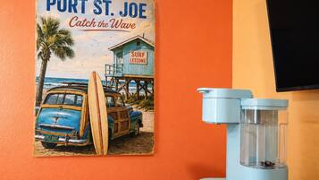 Póster antiguo de Port St. Joe con clases de surf, un coche azul y un filtro de agua azul sobre una mesa.