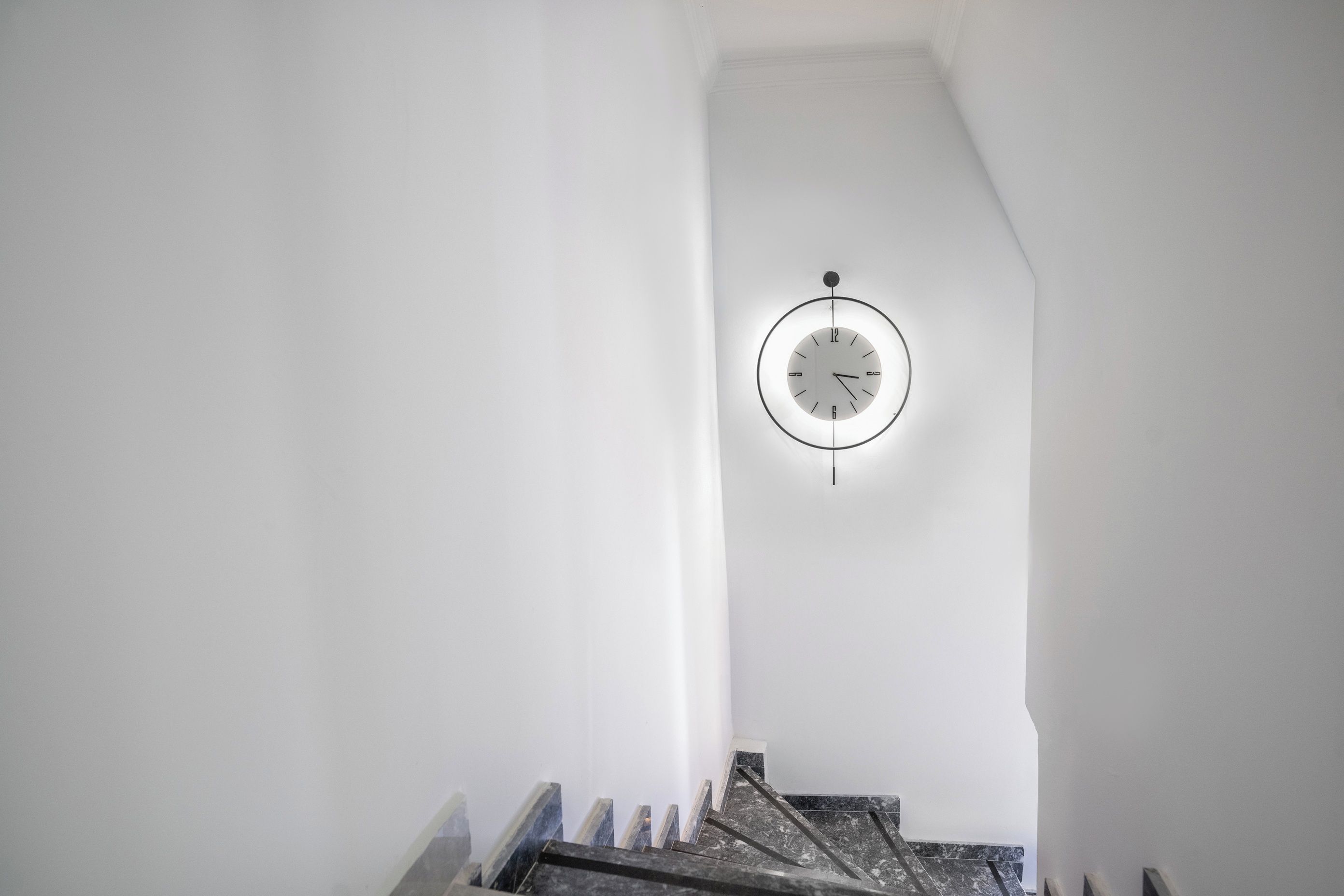 A staircase with a wall-mounted clock.