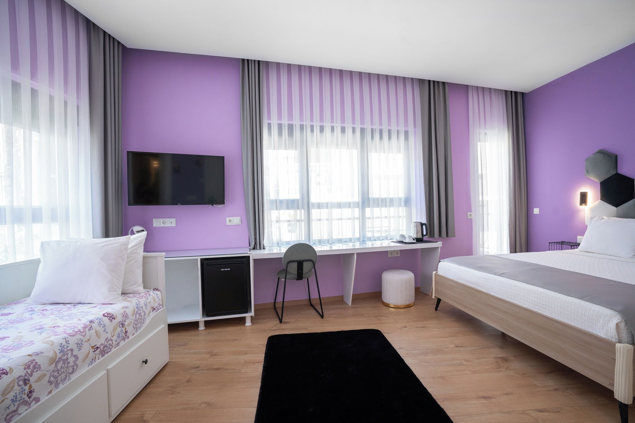 Ein modernes Schlafzimmer mit Bett, Schreibtisch und Fernseher.