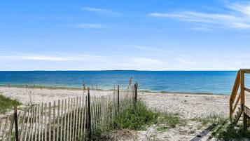 Une plage avec une clôture en bois et un banc, qui mène à l’océan.