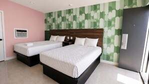 Quarto de hotel com duas camas, cabeceira de madeira, parede com padrão verde e uma porta.
