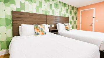Habitación de hotel con dos camas, cabecero de madera y pared con estampado verde.