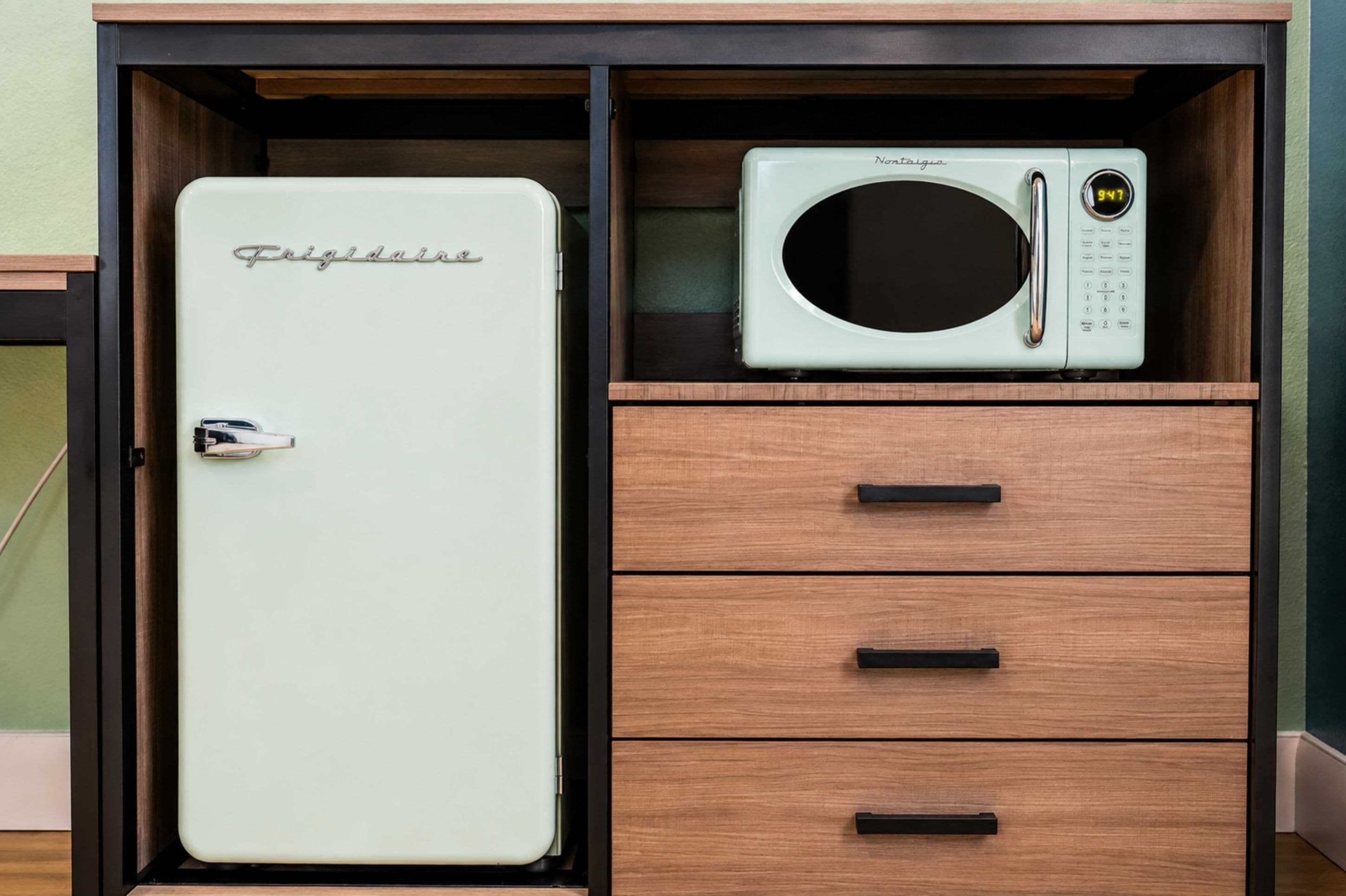 A kitchen with a Frigidaire refrigerator and a microwave on a wooden cabinet.