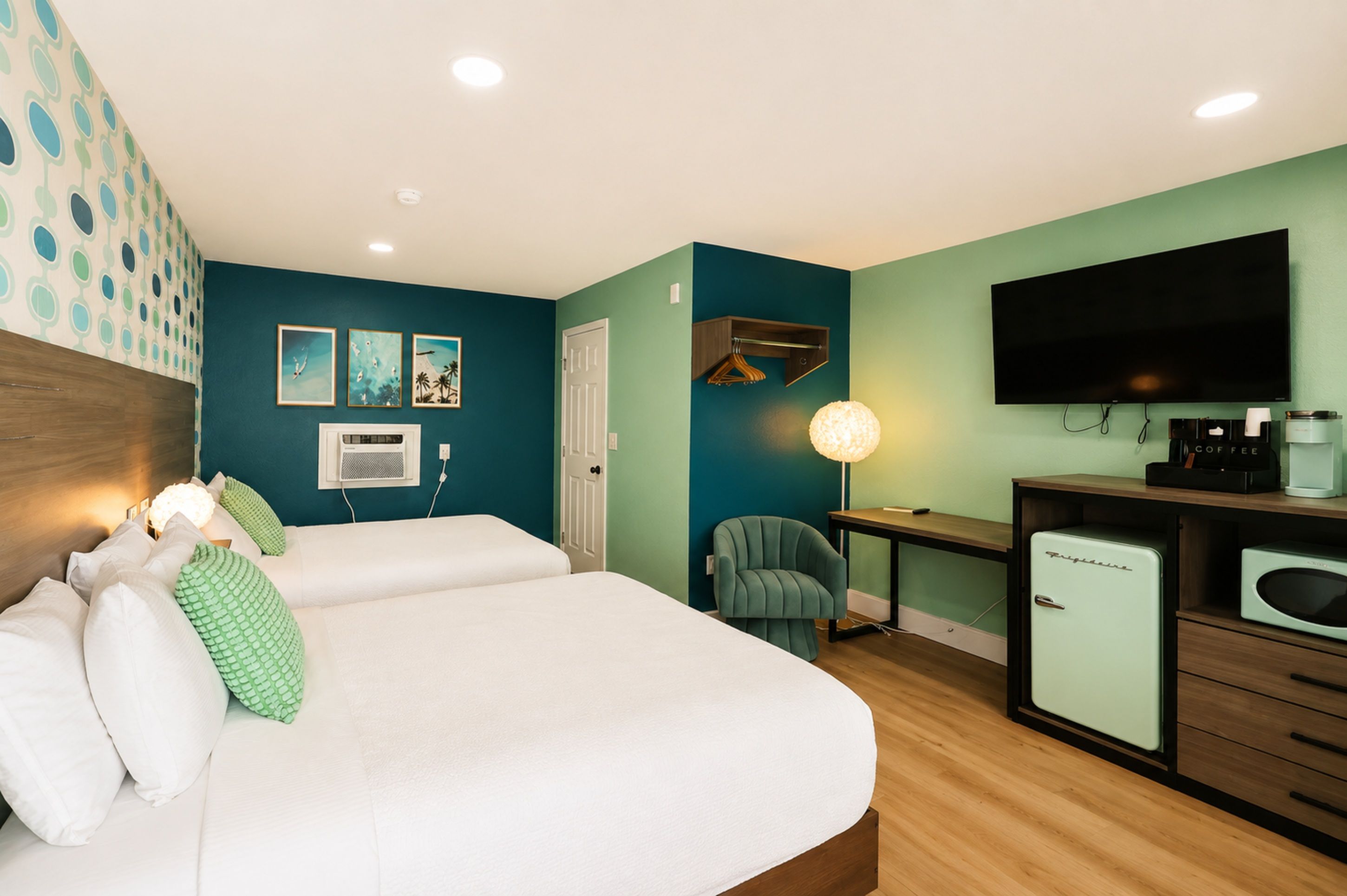 Una habitación de hotel con cama, escritorio, silla, televisión y cafetera.